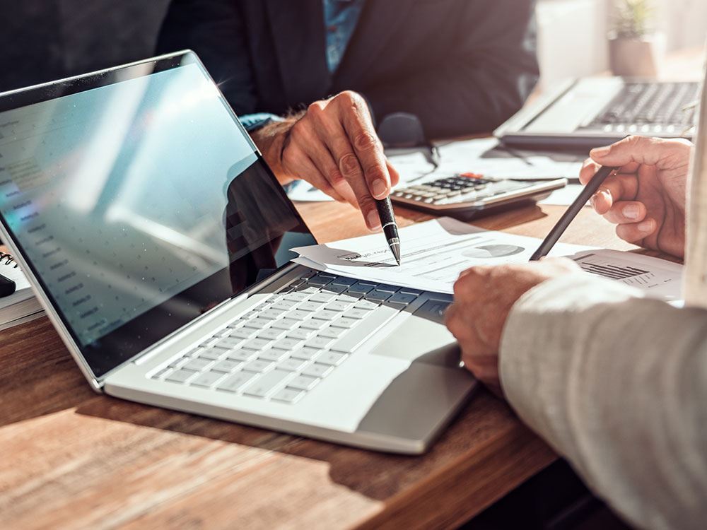 Mão analisando contratos com calculadora e notebook